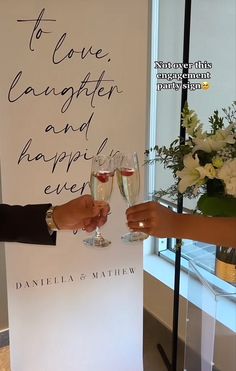 two people holding wine glasses in front of a sign that says to love laughter and happily ever