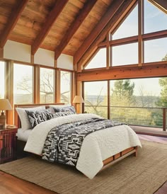 a large bed sitting inside of a bedroom next to a tall window filled with lots of windows