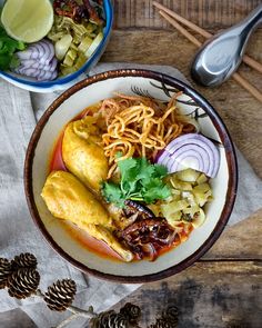 two bowls filled with food on top of a wooden table