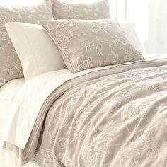 a bed with white sheets and pillows on top of it in front of a window