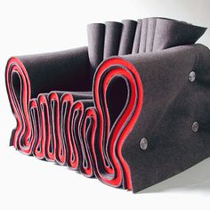 a chair made out of felt with red and black designs on the back, sitting in front of a white background