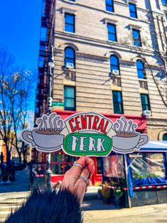 a person holding up a sticker that says central coffee on the side of a building