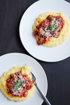 two white plates topped with food on top of a wooden table next to each other