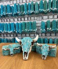 two long horn steer heads are sitting on a wooden table in front of turquoise beads