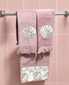 two towels hanging on a towel rack in a pink tiled bathroom with seashells