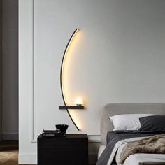 a bedroom with a bed, night stand and lamp on the wall next to it