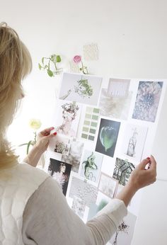 a woman is looking at pictures on the wall with flowers in front of her,