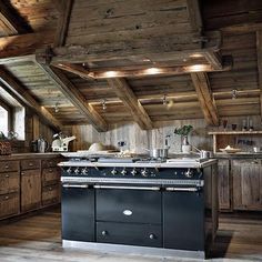 an old fashioned stove is in the middle of a room with wooden walls and beams