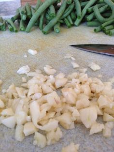 chopped onions and green beans are on the floor next to a pair of knifes