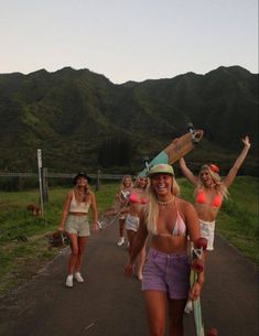 a group of women walking down a road with skateboards on their heads and arms in the air