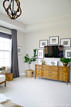 a living room with pictures on the wall and a television mounted to the wall above it