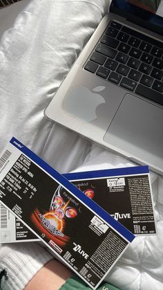 two tickets sitting on top of a bed next to an open laptop computer and keyboard