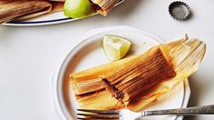 a plate with some tamales and limes on it