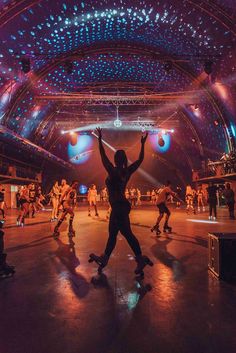 a group of people dancing on stage with their arms in the air and lights above them