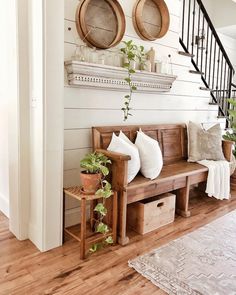 a wooden bench sitting in the middle of a living room next to a stair case