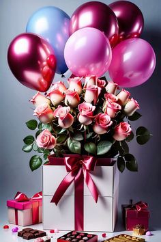 a bouquet of pink roses and balloons in a box with some chocolates on the table