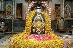 a statue made out of yellow flowers in front of a building with other statues behind it