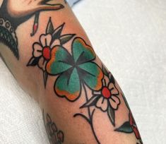 a close up of a person's arm with tattoos on it and flowers in the middle