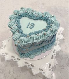 a heart shaped cake with the number nineteen on it sitting on a white doily