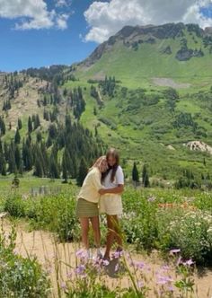 two girls hugging each other in the mountains