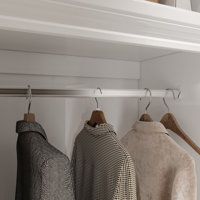 three sweaters are hanging on a rail in front of a shelf with two coats