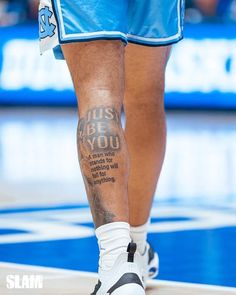 the legs and ankles of a basketball player with tattoos on his leg, while wearing blue shorts