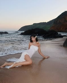 a woman laying on top of a sandy beach next to the ocean