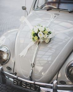 a bouquet of white flowers is tied to the front of an old fashioned vw bug