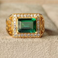 a ring with an emerald surrounded by white and yellow diamonds on top of a piece of cloth