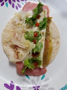 a taco with meat, lettuce and tomatoes on it sitting on a plate