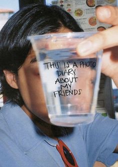 a man holding up a cup with writing on the inside and in front of his face