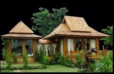 two small wooden buildings sitting on top of a lush green field