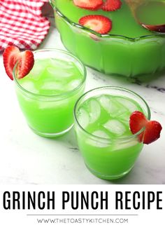 two glasses filled with green punch and strawberries on the rim, sitting next to each other