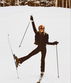 a woman on skis standing in the snow with her arms up and legs spread out