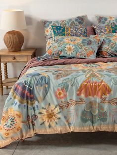 a bed covered in blue and orange floral comforter sets with pillows on each side