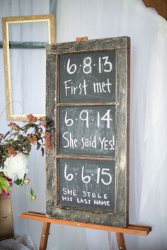 a wooden sign with numbers on it sitting next to a potted plant and mirror