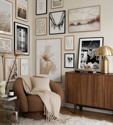 a living room filled with lots of pictures on the wall and a chair in front of it