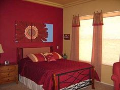 a bed room with a neatly made bed and two red chairs next to the window