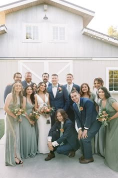 a group of people standing next to each other in front of a white building with a barn