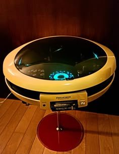 an electronic device is sitting on top of a wooden table with a red plate underneath it