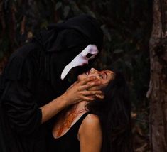 a woman dressed as a nun hugging a man with blood on his face in the woods