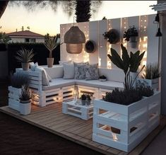 a white couch sitting on top of a wooden deck next to plants and potted plants