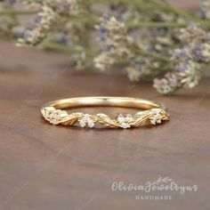 a yellow gold wedding band with flowers on the side, sitting next to some lavenders