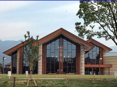 a large building with many windows in front of trees and grass on the side of it