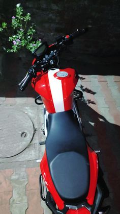 a red motorcycle parked next to a brick walkway