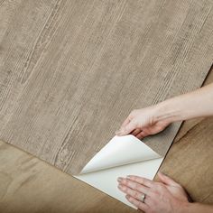 a woman is laying down some paper on the floor