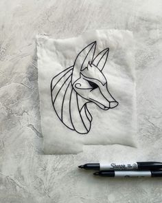 a drawing of a wolf on a piece of paper next to a marker and pen