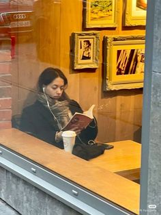 a woman sitting in front of a window reading a book