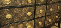 an ornate gold and black chest of drawers with brass knobs on the doors,