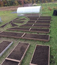 several rows of dirt in front of a green house with a clear cover over it